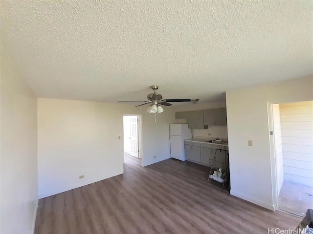 unfurnished living room featuring a textured ceiling, dark hardwood / wood-style floors, ceiling fan, and sink