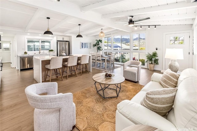 living room with sink, vaulted ceiling with beams, ceiling fan, light wood-type flooring, and wood ceiling