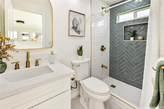 bathroom with a tile shower, vanity, and toilet