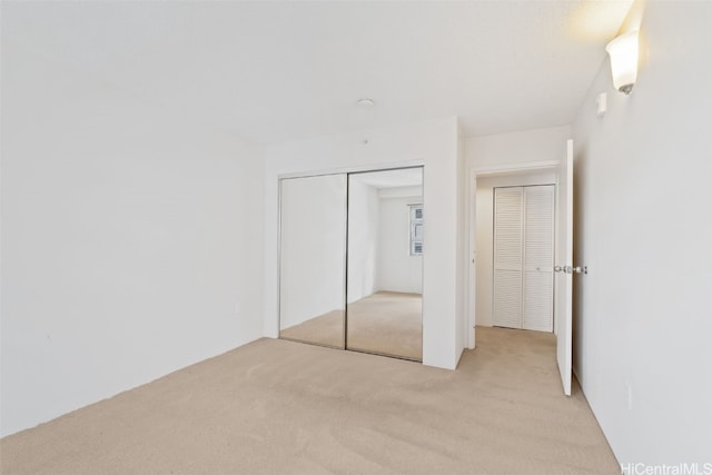 unfurnished bedroom with light carpet and a closet