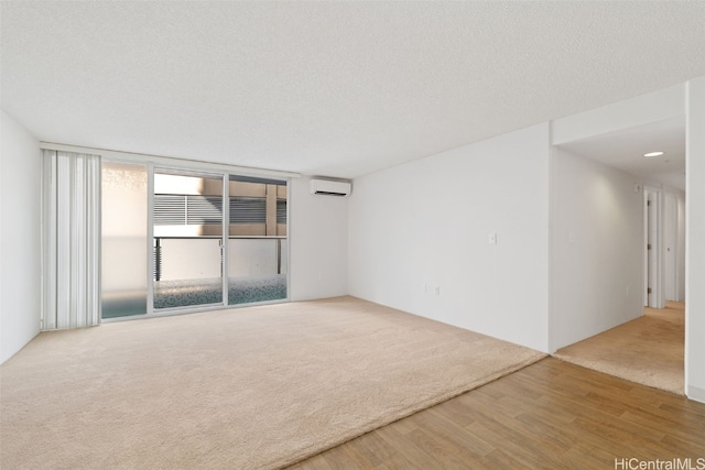 unfurnished room with a wall unit AC, floor to ceiling windows, wood-type flooring, and a textured ceiling