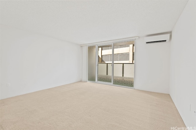 spare room featuring a wall mounted AC, light carpet, and a textured ceiling