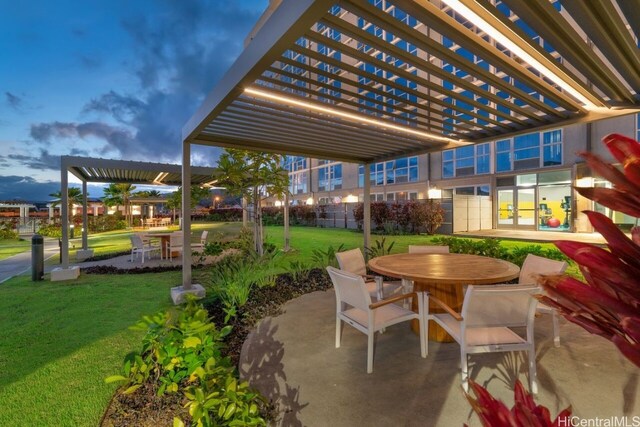 patio terrace at dusk with a pergola and a lawn