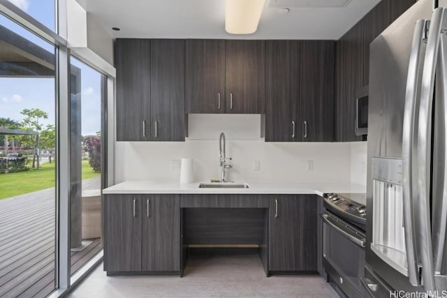 kitchen featuring light countertops, electric range oven, stainless steel refrigerator with ice dispenser, and a sink