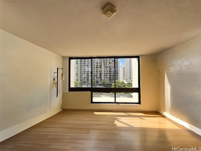 empty room with hardwood / wood-style floors and a textured ceiling