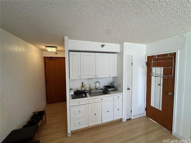 kitchen featuring white cabinetry, sink, a textured ceiling, and light hardwood / wood-style floors