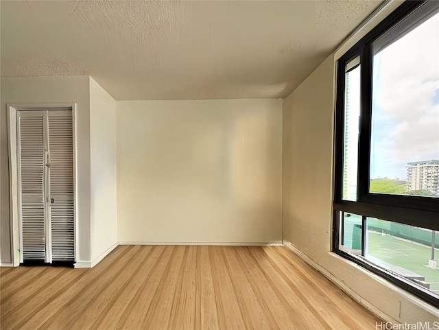 unfurnished room featuring a textured ceiling and light hardwood / wood-style floors