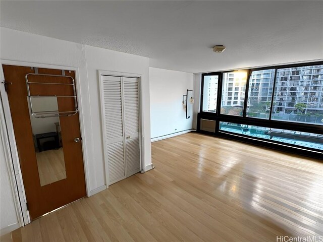 unfurnished bedroom featuring light hardwood / wood-style floors, floor to ceiling windows, and multiple closets