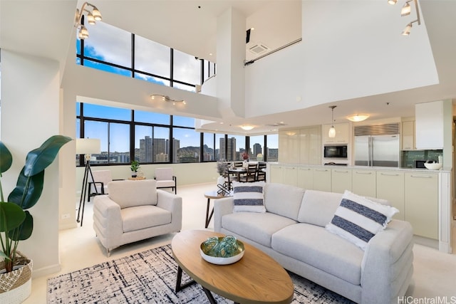 living room with light colored carpet, a view of city, visible vents, and a towering ceiling