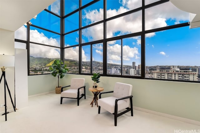 sitting room featuring a view of city, a high ceiling, carpet, and baseboards