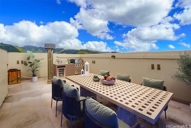 view of patio with a mountain view, exterior kitchen, grilling area, and wine cooler