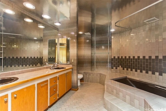 bathroom featuring tiled bath, tile patterned flooring, vanity, and toilet