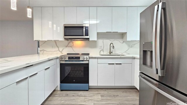 kitchen featuring white cabinetry, sink, stainless steel appliances, backsplash, and decorative light fixtures