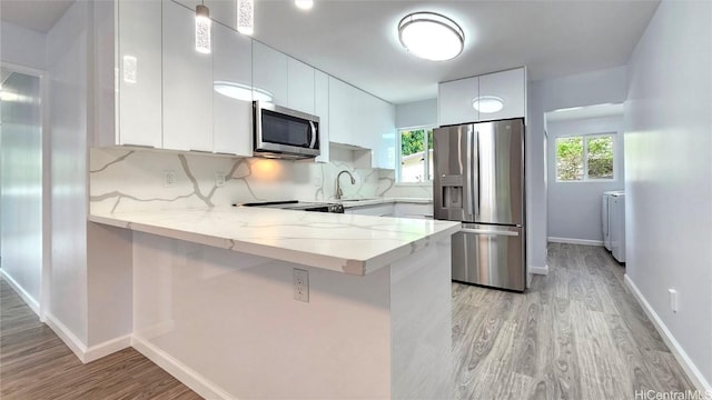 kitchen featuring white cabinets, stainless steel appliances, kitchen peninsula, and tasteful backsplash