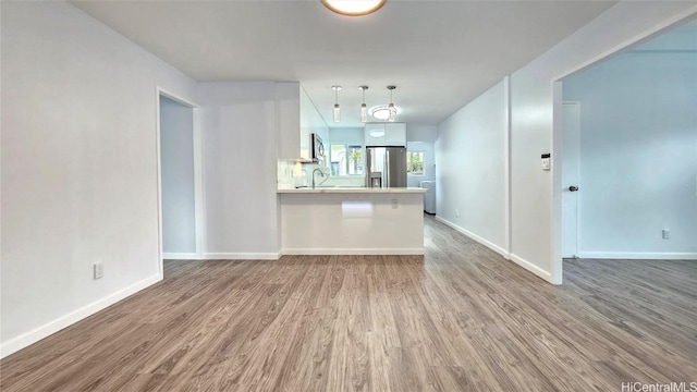 kitchen with hardwood / wood-style floors, a kitchen breakfast bar, sink, white cabinetry, and stainless steel appliances