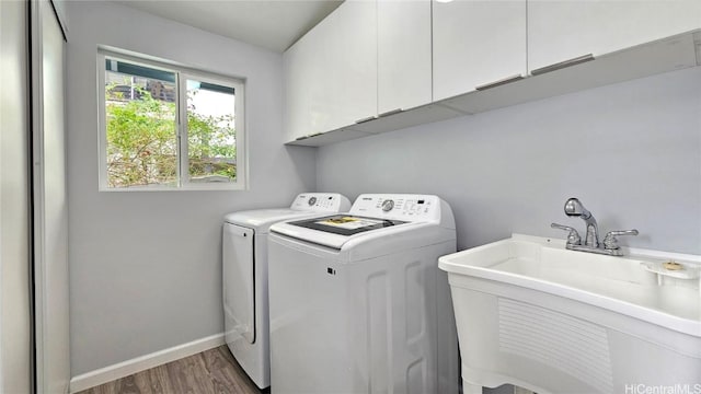 clothes washing area with dark hardwood / wood-style flooring, cabinets, sink, and washing machine and clothes dryer