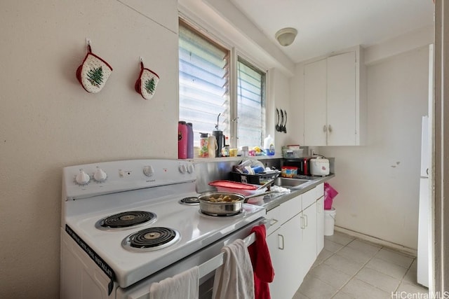 kitchen with electric stove, white cabinetry, and light tile patterned floors