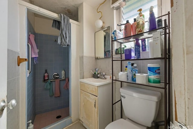 bathroom featuring backsplash, toilet, vanity, and tiled shower