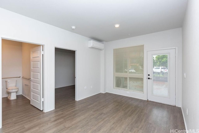 unfurnished room featuring a wall mounted air conditioner and hardwood / wood-style floors