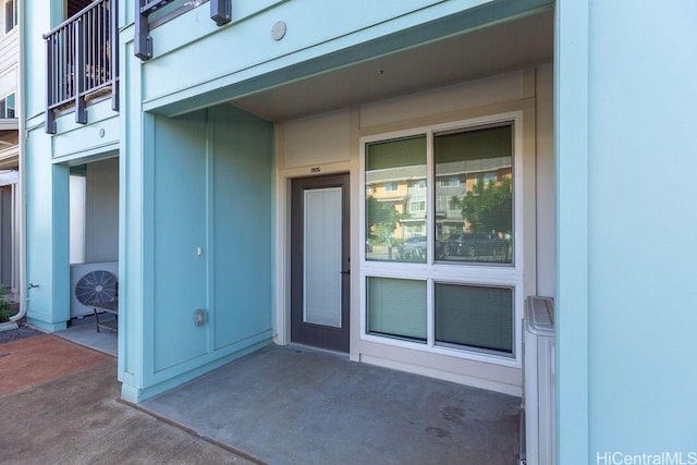 view of exterior entry with a balcony and ac unit