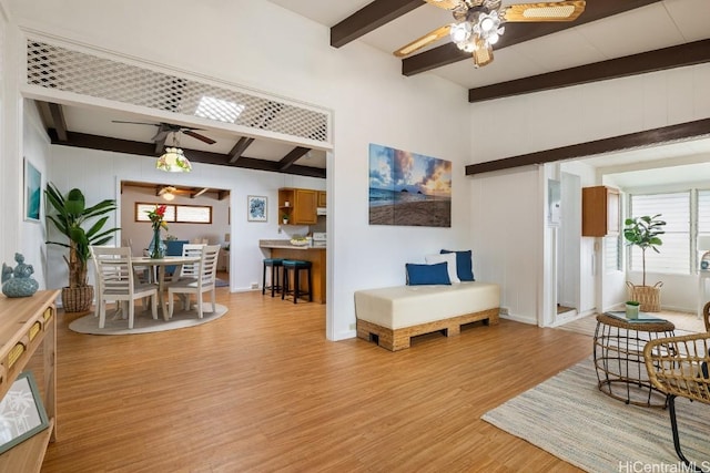 living room featuring beamed ceiling, ceiling fan, and light wood-type flooring