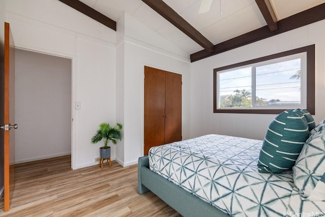 bedroom with wood-type flooring, vaulted ceiling with beams, ceiling fan, and a closet