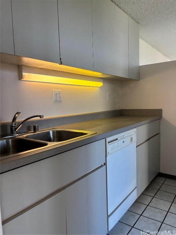 kitchen with light tile patterned flooring, a textured ceiling, white dishwasher, and sink