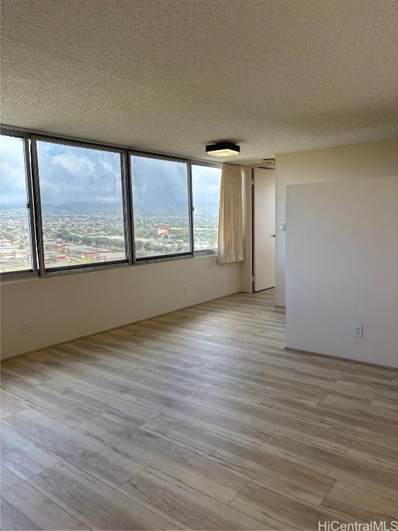 unfurnished room with light hardwood / wood-style flooring and a textured ceiling