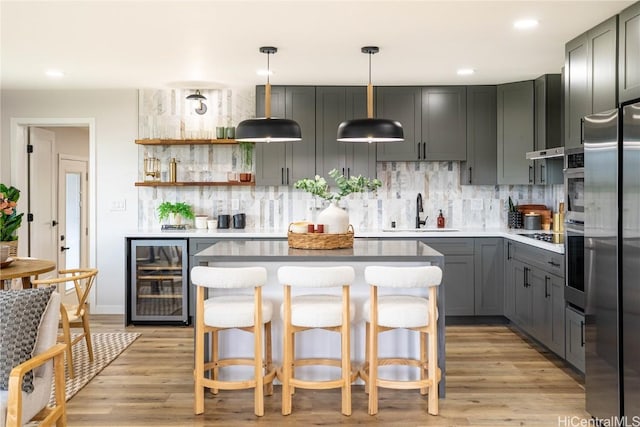 kitchen featuring sink, wine cooler, decorative light fixtures, gray cabinets, and light wood-type flooring