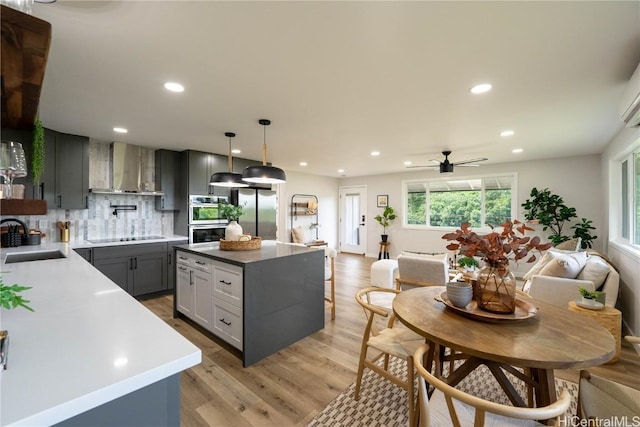 kitchen featuring sink, wall chimney exhaust hood, decorative backsplash, appliances with stainless steel finishes, and decorative light fixtures