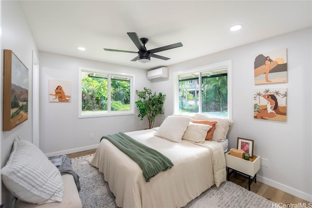 bedroom with a wall mounted air conditioner, light wood-type flooring, and ceiling fan