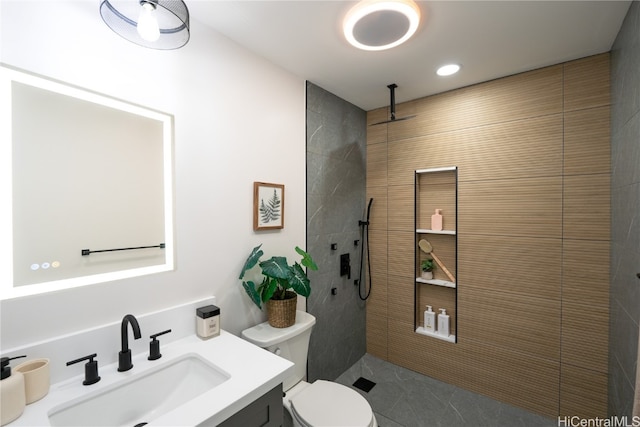 bathroom featuring toilet, vanity, and tiled shower