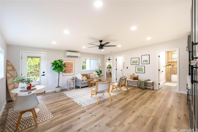 living room featuring a wall unit AC, a wealth of natural light, ceiling fan, and light hardwood / wood-style floors