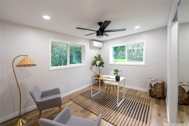 office area with a wall mounted air conditioner, light hardwood / wood-style floors, and ceiling fan