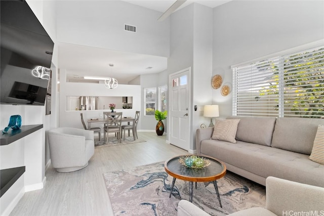 living room featuring a healthy amount of sunlight, light hardwood / wood-style floors, and a high ceiling