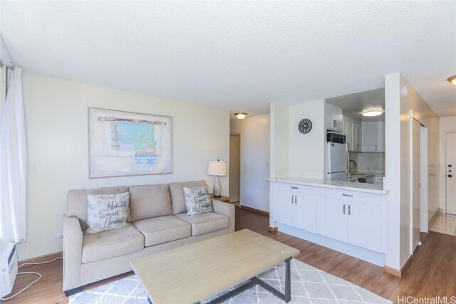 living room featuring hardwood / wood-style floors, a textured ceiling, and sink