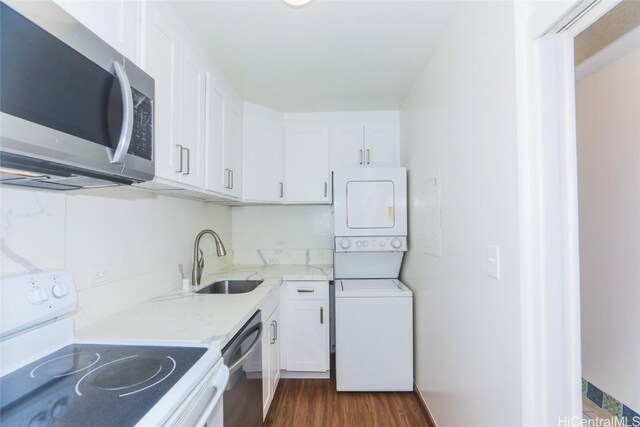 kitchen with white cabinets, sink, stacked washer / drying machine, dark hardwood / wood-style flooring, and stainless steel appliances