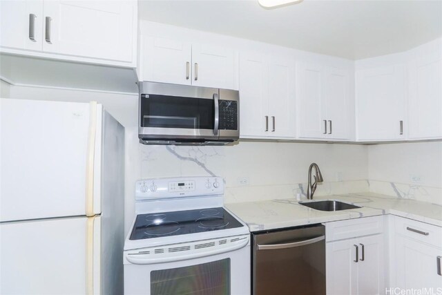 kitchen with light stone countertops, appliances with stainless steel finishes, white cabinetry, and sink