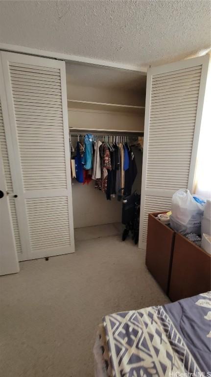 bedroom with light carpet, a closet, and a textured ceiling