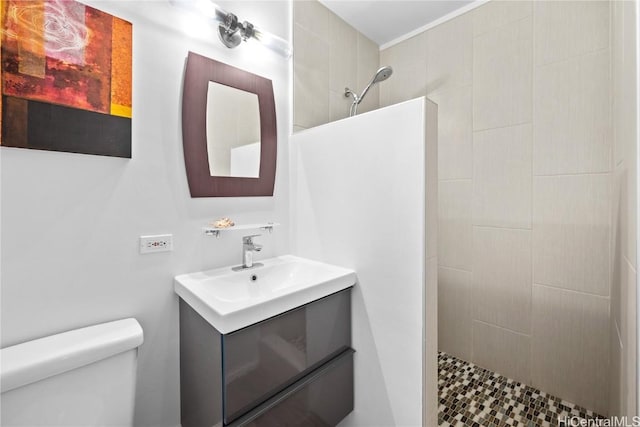 bathroom with a tile shower, vanity, and toilet