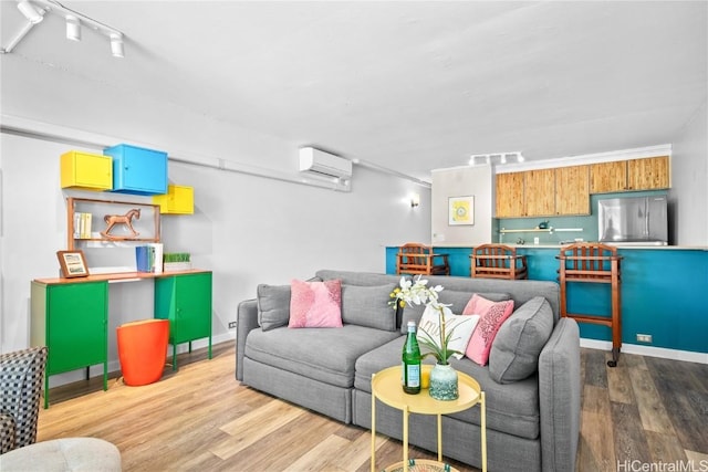 living room featuring light wood-type flooring, rail lighting, and a wall mounted AC