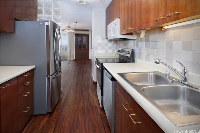 kitchen featuring dark wood-type flooring, a sink, tasteful backsplash, stainless steel appliances, and light countertops