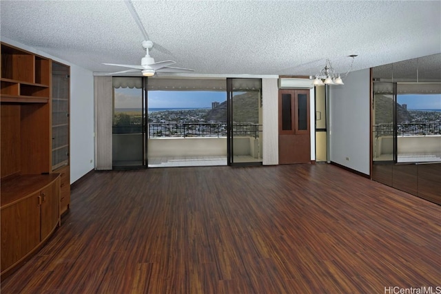 unfurnished living room featuring dark hardwood / wood-style flooring, ceiling fan with notable chandelier, a wall unit AC, and a textured ceiling