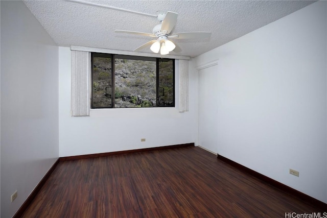 empty room featuring baseboards, dark wood-type flooring, a ceiling fan, and a textured ceiling