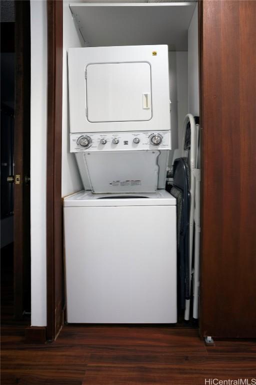 washroom with dark wood-type flooring, laundry area, and stacked washing maching and dryer