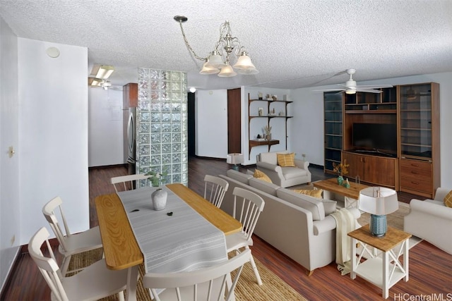 dining space with a textured ceiling, wood finished floors, and ceiling fan with notable chandelier