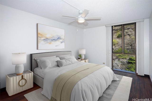 bedroom with dark wood-type flooring, ceiling fan, floor to ceiling windows, and a textured ceiling