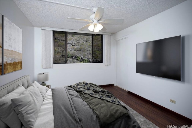 bedroom featuring dark hardwood / wood-style flooring, ceiling fan, multiple windows, and a textured ceiling