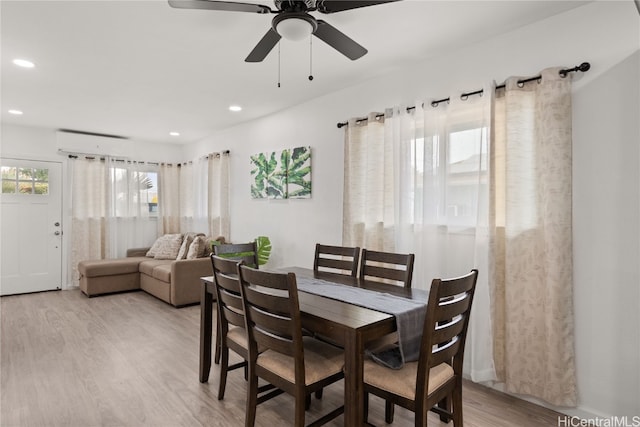 dining space with ceiling fan, an AC wall unit, and light hardwood / wood-style flooring