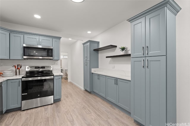 kitchen with gray cabinetry, stainless steel appliances, and light wood-type flooring